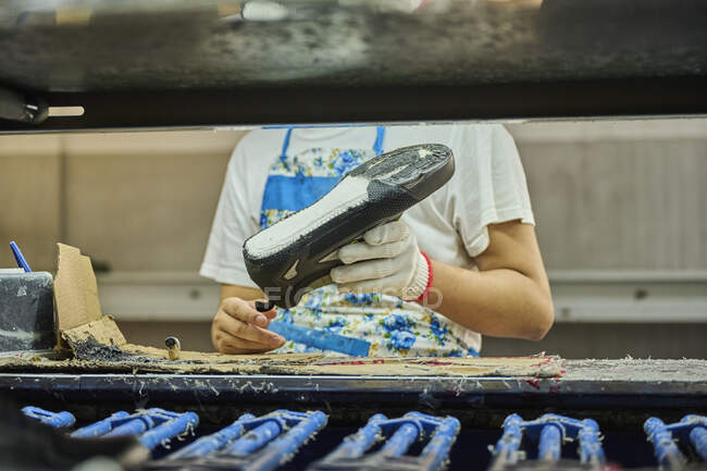 Dettaglio del lavoratore che applica la colla alla suola delle scarpe in una linea di produzione di fabbrica di scarpe cinesi — Foto stock