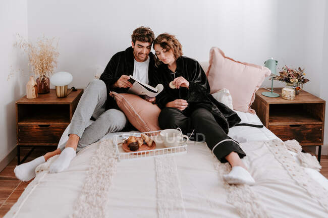 Високий кут ніжної пари, що розслабляється на ліжку разом під час сніданку вранці — стокове фото