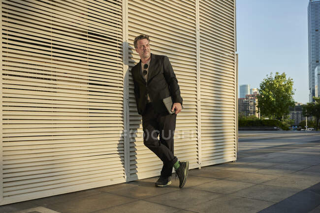 Homme d'affaires debout à l'extérieur de l'immeuble de bureaux au coucher du soleil — Photo de stock