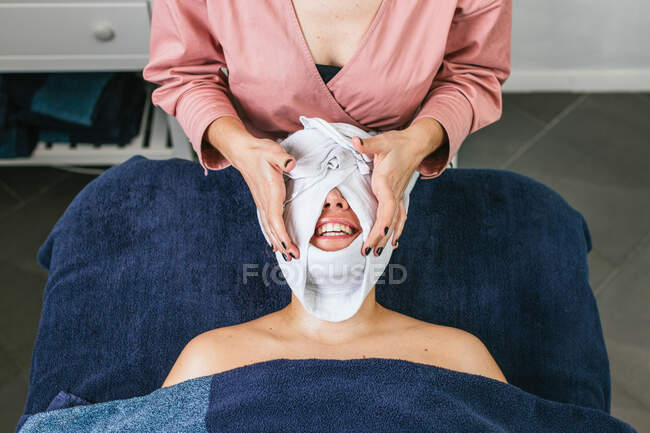 Von oben von der Ernte unkenntlich Kosmetikerin dampfenden Gesicht der Kundin mit heißem Handtuch während der Hautpflege-Behandlung im Schönheitssalon — Stockfoto