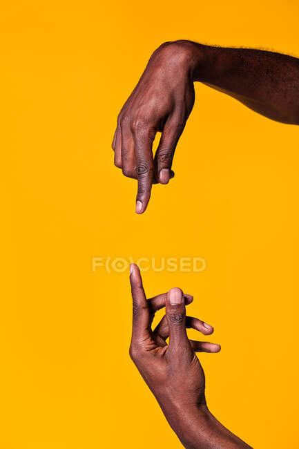 Gegensätzliche Hände eines afrikanisch-amerikanischen Mannes, die auf einander zeigen, mit Zeigefinger auf gelbem Hintergrund — Stockfoto