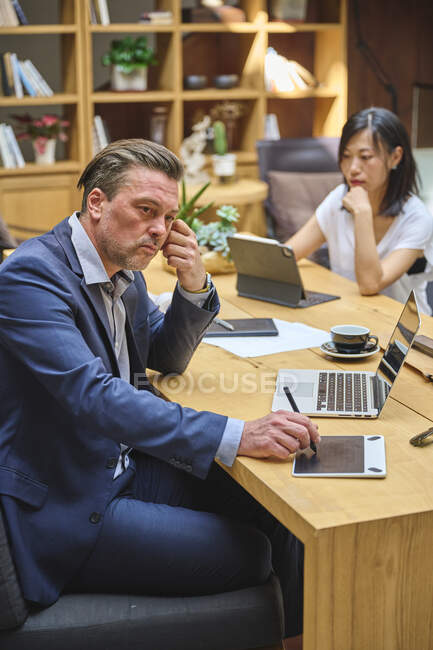Designer am Schreibtisch, der mit seinem Assistenten am Computer arbeitet — Stockfoto