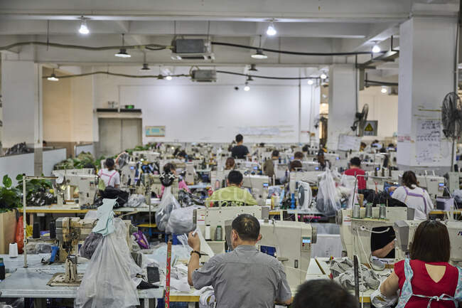 View of busy sewing room in Chinese shoes factory — Stock Photo