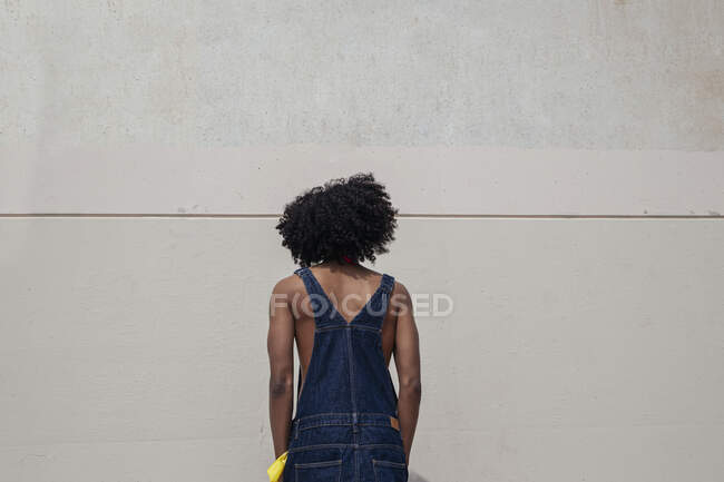 Vista posteriore del giovane maschio etnico in abiti retrò con acconciatura Afro appoggiata su muro di cemento — Foto stock