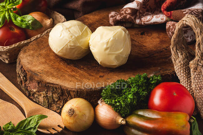 Яйца сыра моцарелла среди различных здоровых продуктов и органические лопатки с листьями базилика на столе — стоковое фото