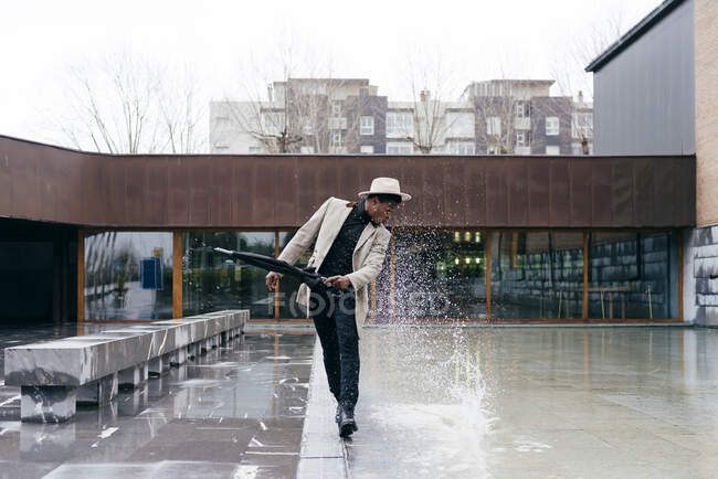 Retrato de hombre negro elegante con abrigo gris y paraguas en la calle - foto de stock