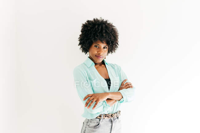 Feliz jovem afro-americano feminino com belo cabelo afro na roupa da moda olhando para a câmera no fundo branco — Fotografia de Stock