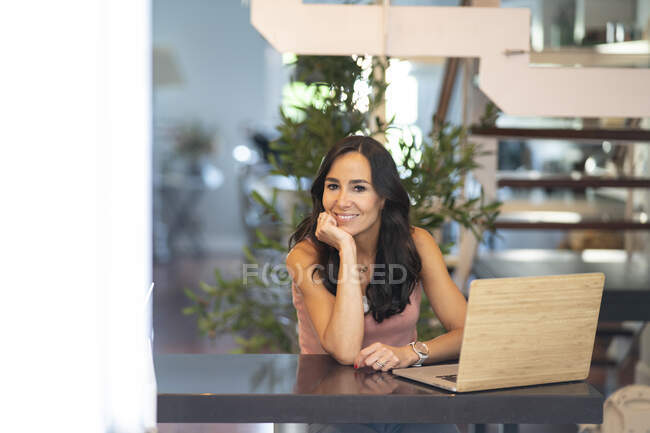 Щаслива фрілансерка сидить за столом вдома і переглядає планшет під час роботи над бізнес-проектом — стокове фото