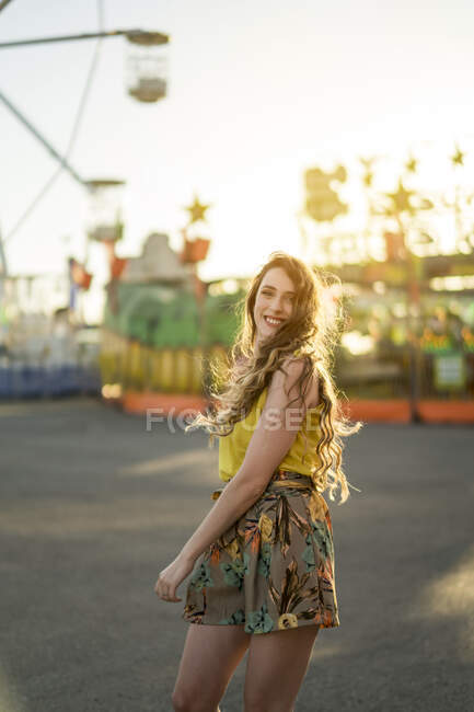 Mulher encantada dançando olhando para a câmera com braços levantados no parque de diversões e desfrutando de fim de semana de verão — Fotografia de Stock