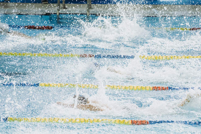 Vue de dessus des personnes plongeant dans l'eau avec éclaboussures dans la piscine avec des voies de baignade — Photo de stock