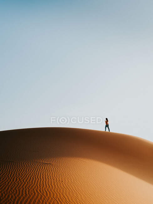 Unrecognizable tourist walking on sand dune against cloudless blue sky in desert near Marrakesh, Morocco — Stock Photo