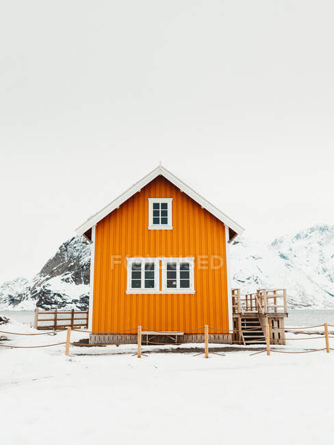 Yellow cabin located near mountain range snowy seacoast on Lofoten Islands, Norway — Stock Photo