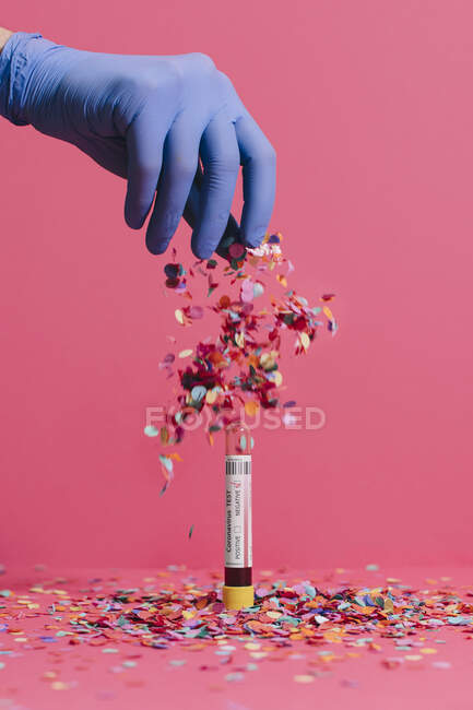 Mãos de médico irreconhecível cortadas jogando confete no teste de sangue negativo coronavírus em fundo rosa — Fotografia de Stock