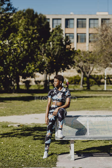 Jovem aptidão afro-americana mulher descansando depois de fazer exercício no banco do parque — Fotografia de Stock