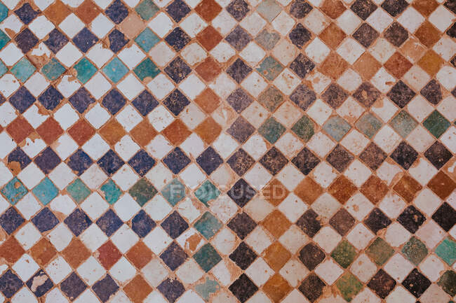 Desde arriba superficie erosionada de suelo de baldosas ornamentales dentro del antiguo edificio en Marrakech, Marruecos - foto de stock