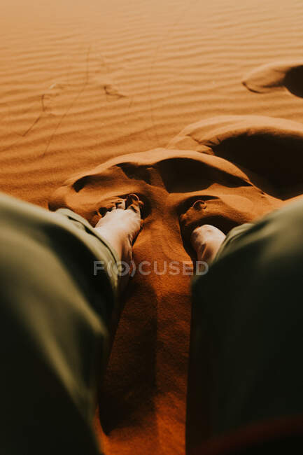 De acima de turista irreconhecível sentado na duna de areia e admirando majestoso cenário do pôr do sol no deserto em Marrocos — Fotografia de Stock