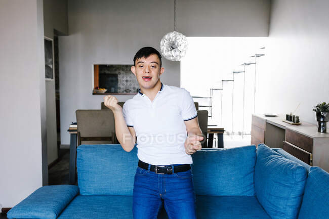Rapaz adolescente étnico positivo com síndrome de Down dançando na sala de estar em casa e se divertindo no fim de semana — Fotografia de Stock