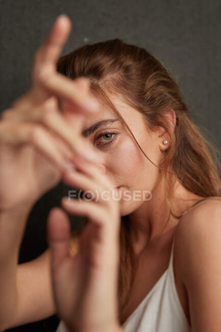 Jeune femme tendre tendre tendre la main vers la caméra sur fond gris en studio — Photo de stock