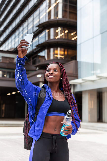 Fröhliche muskulöse Afroamerikanerin macht Selfie mit Energy Drink auf der Straße — Stockfoto