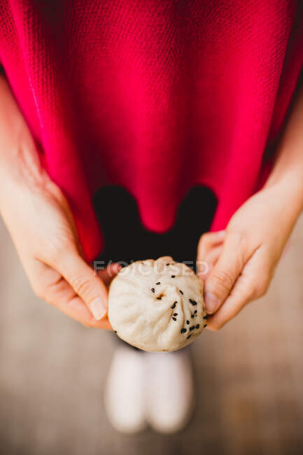 Unrecognizable female showing yummy Sheng Jian Bao to camera while standing on street — Stock Photo