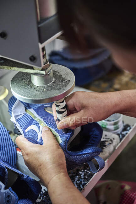 Detail eines Arbeiters, der Löcher für Schnürsenkel in der chinesischen Schuhfabrik macht — Stockfoto