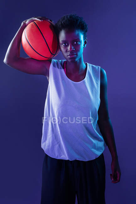 Donna nera con abito da basket in studio utilizzando gel di colore e luci del proiettore — Foto stock