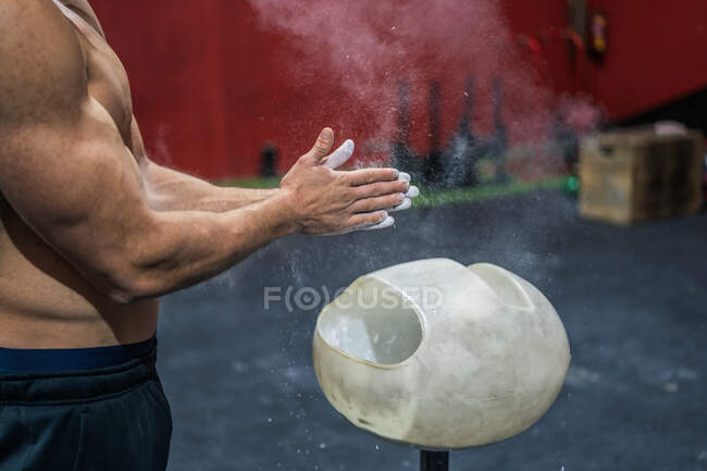 Seitenansicht eines nicht wiederzuerkennenden muskulösen Athleten, der beim Gewichtheben-Training im Fitnessstudio Kreide auf den Händen verteilt — Stockfoto