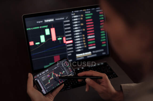 Faceless crop broker utilizzando il telefono cellulare mentre si lavora con grafico finanziario durante il trading — Foto stock