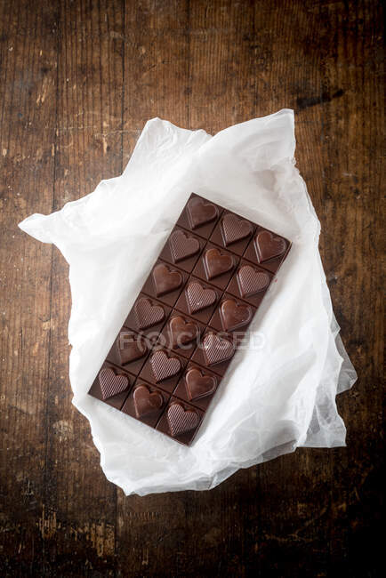 Vista dall'alto di deliziosa barretta di cioccolato caramelle a forma di cuore su sfondo tavolo di legno — Foto stock