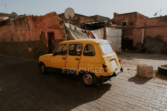 Vintage car parked near destroyed houses on street of ghetto in Marrakesh, Morocco — Stock Photo