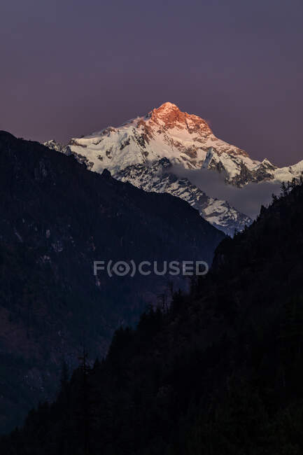 Rocky Himalayas mountains covered with snow lit by bright orange sundown light in Nepal — Stock Photo
