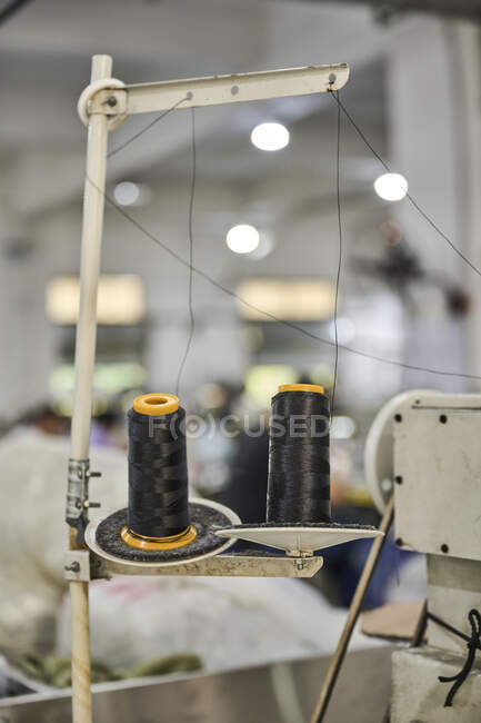 Detalle de los paquetes de hilo en la máquina de coser en la fábrica de zapatos chinos - foto de stock