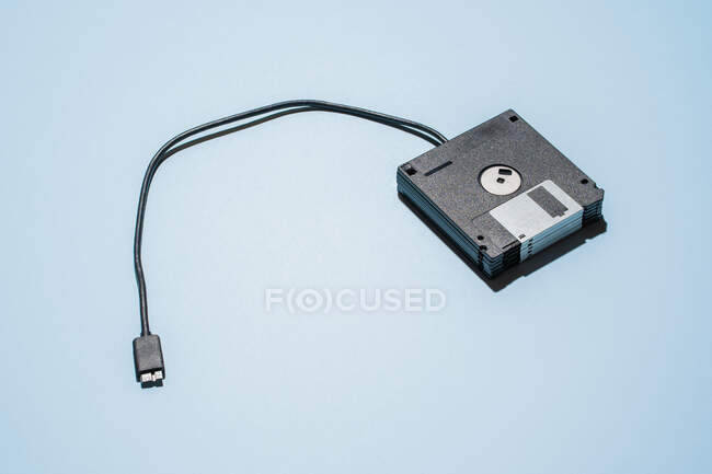 Dall'alto di pila di floppy disk neri con cavo usb posizionato su sfondo azzurro — Foto stock