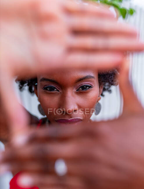 Афроамериканка демонстрирует жест фотографии руками, глядя в камеру — стоковое фото