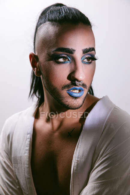 Portrait of glamorous transgender bearded woman in sophisticated make looking away against neutral background — Stock Photo