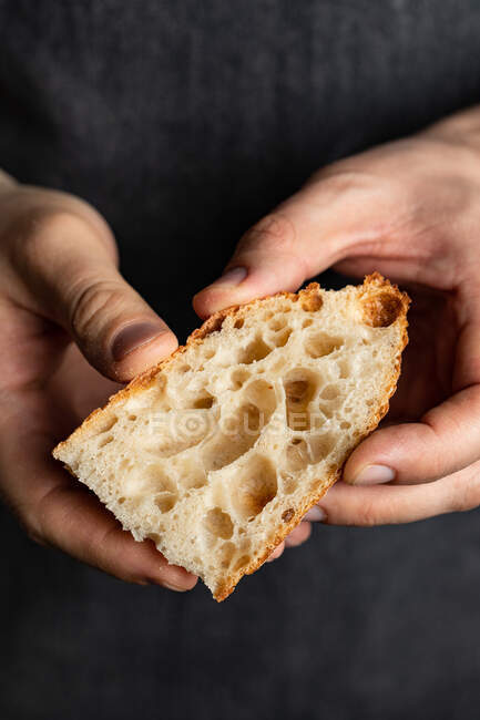 Unbekannter Koch in Schürze steht mit Stück frisch gebackenem Brot — Stockfoto