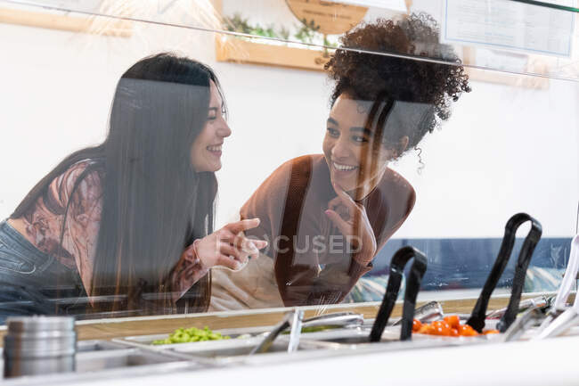 Des amies multiraciales debout au comptoir et choisissant de la nourriture au restaurant tout en passant le week-end ensemble — Photo de stock