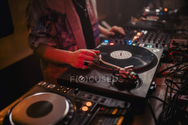 Vista lateral da colheita DJ masculino misturando música no controlador durante concerto em boate escuro — Fotografia de Stock