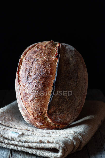 Pão de centeio caseiro caseiro rústico sourdough em cobertor em fundo preto — Fotografia de Stock