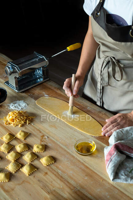 Pessoa irreconhecível preparando raviolis e massas em casa. Ela está pintando a massa com ovos — Fotografia de Stock