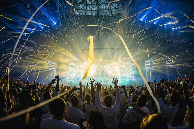 Dançando multidão com braços levantados jogando fitas durante a performance musical ao vivo na moderna sala de concertos — Fotografia de Stock