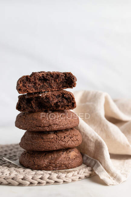 Купка шоколадного житнього печива, розміщеного на плетеній тарілці біля серветки на білому тлі — стокове фото