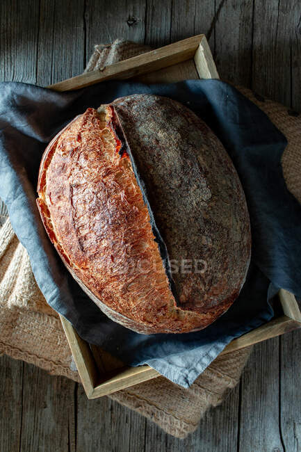From above rustic homemade fresh sourdough rye loaf on napkin in wooden box — Stock Photo