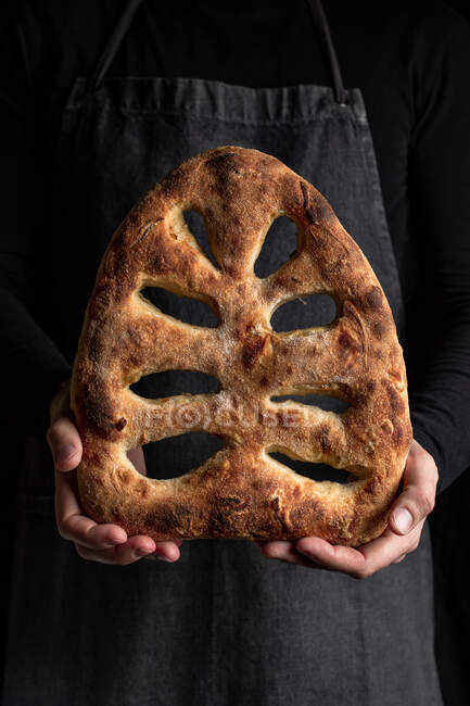 Crop chef maschio in grembiule in piedi con pane appena sfornato di pane fougasse — Foto stock
