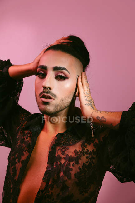 Ritratto di donna barbuta transgender glamour in sofisticato make up posa guardando la fotocamera contro sfondo rosa in studio — Foto stock