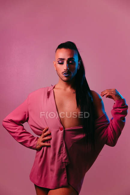 Retrato de mujer barbuda transgénero glamorosa en maquillaje sofisticado posando con los ojos cerrados sobre fondo rosa en el estudio - foto de stock