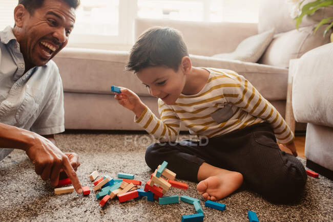 Vista laterale di padre e figlio che giocano con i pezzi da costruzione nella sala da pranzo della casa — Foto stock