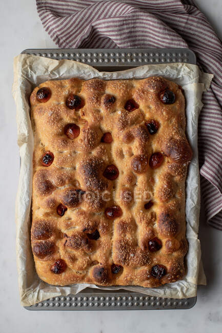 Top view of freshly baked traditional bread with tomatoes placed on baking paper — Stock Photo