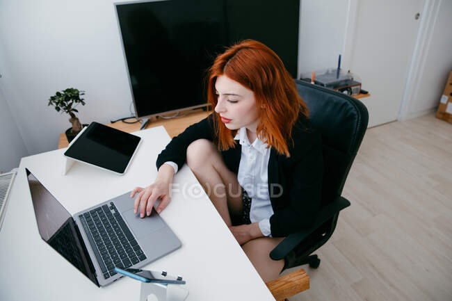 From above young female entrepreneur working on netbook at desk with tablet and smartphone at home — Stock Photo