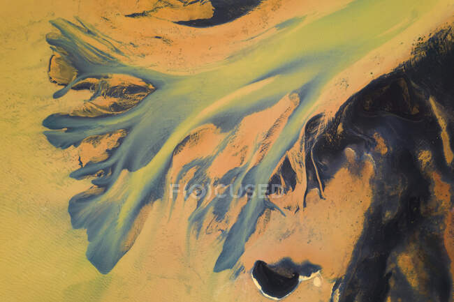 Von oben Luftaufnahme eines Flusses mit orangefarbenem Wasser, das durch die raue Landschaft Islands fließt — Stockfoto